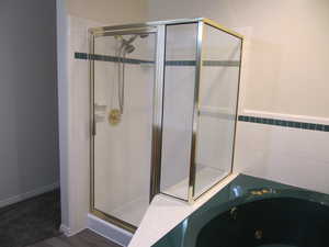 Full bathroom with a shower stall, a tub with jets, and tile walls