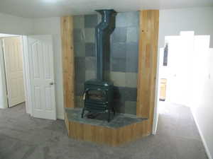 Unfurnished living room featuring a wood stove and carpet flooring