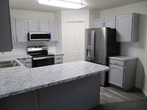 Kitchen with decorative backsplash, stainless steel appliances, light countertops, and gray cabinets