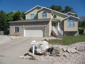 View of front facade featuring driveway, an attached garage, and brick siding