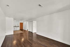 Unfurnished living room with dark wood-type flooring and baseboards