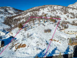 Snowy aerial view featuring property parcel outlined and a mountain view