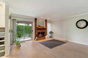 Unfurnished living room featuring light wood-type flooring, crown molding, a fireplace, and stairway