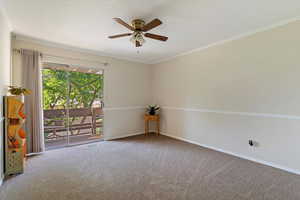 Carpeted empty room featuring crown molding and a ceiling fan