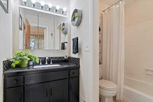 Bathroom featuring vanity, shower / tub combo with curtain, and a textured wall