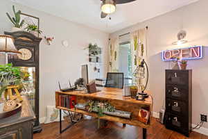 Home office featuring dark wood-type flooring and a ceiling fan