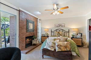 Carpeted bedroom featuring ornamental molding, access to exterior, a fireplace, and a ceiling fan