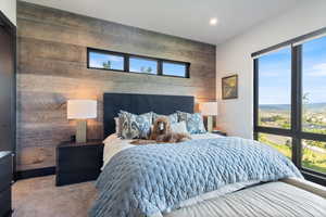 Carpeted bedroom with wooden walls and an accent wall