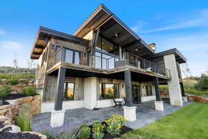 Back of property with a patio, stone siding, and a lawn