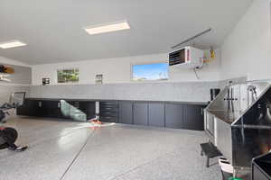 Misc room with pet washing area, a heating unit, rail lighting, and dark aggregate flooring