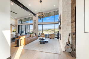 Living room with beamed ceiling, a mountain view, a towering ceiling, light wood-style floors, and recessed lighting