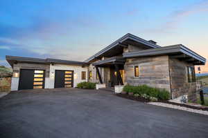 Contemporary home with asphalt driveway, stone siding, and an attached garage