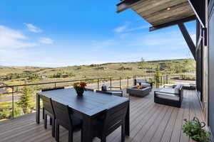Wooden terrace featuring a view of rural / pastoral area, outdoor dining space, and a fire pit