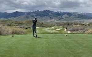 View of community with golf course view, a mountain view, and a yard