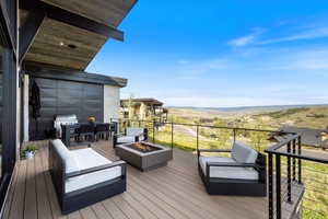 Wooden terrace featuring an outdoor fire pit, area for grilling, and a mountain view