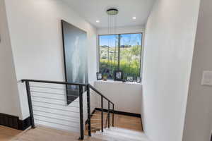 Staircase with wood finished floors and recessed lighting