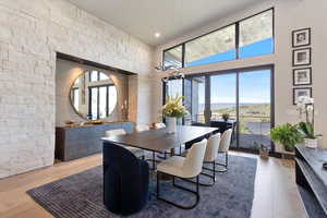 Dining room with wood finished floors, a towering ceiling, and recessed lighting