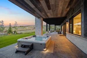 Patio terrace at dusk with a hot tub, a yard, and a patio