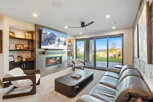 Living area featuring carpet flooring, built in shelves, a tiled fireplace, recessed lighting, and a ceiling fan