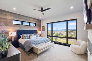 Carpeted bedroom with wooden walls, an accent wall, a ceiling fan, recessed lighting, and a mountain view