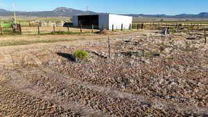 View of yard featuring a mountain view, an outdoor structure, a view of rural / pastoral area, and an outbuilding
