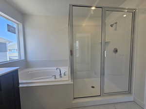 Bathroom with a stall shower, a bath, and vanity