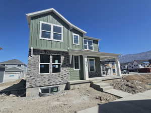 View of front of property featuring a porch, board and batten siding, a residential view, and a mountain view