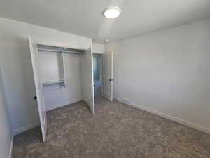 Unfurnished bedroom featuring dark carpet, a closet, and a textured ceiling
