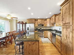 Kitchen with a breakfast bar, appliances with stainless steel finishes, a kitchen island, recessed lighting, and light wood-style floors