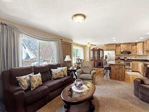 Living area featuring light wood-type flooring, a textured ceiling, ceiling fan, and recessed lighting