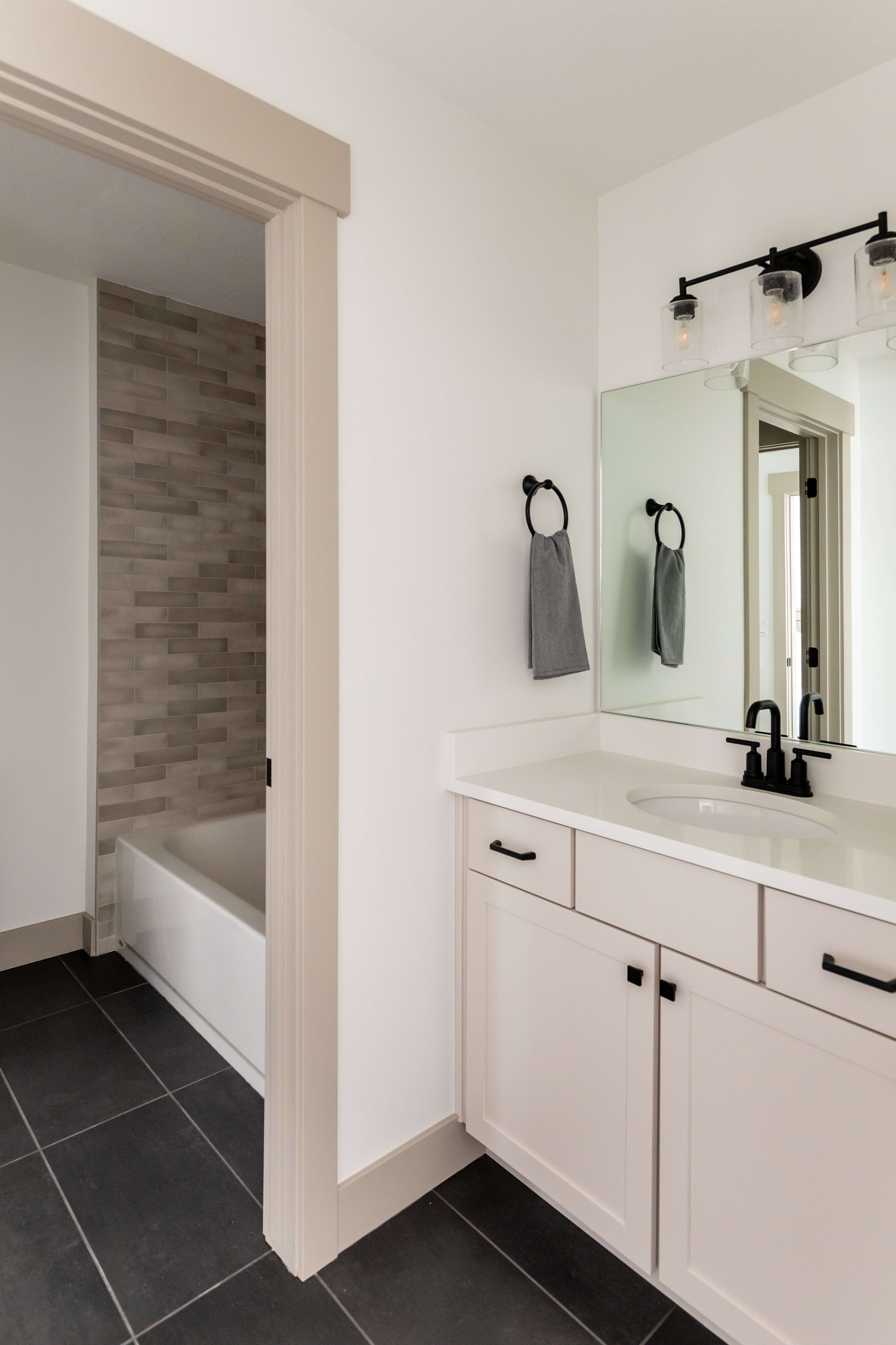 Bathroom with vanity, dark tile patterned flooring, and shower / bathtub combination