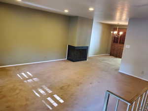 Unfurnished living room featuring a multi sided fireplace, a chandelier, carpet, and recessed lighting