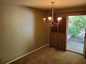 Unfurnished dining area with carpet and a chandelier