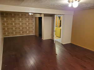 Finished basement featuring dark wood-style flooring, a textured ceiling, and washing machine and clothes dryer