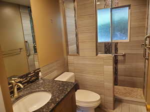 Full bath with vanity, a walk in shower, and tile walls