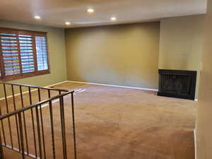 Unfurnished living room with a multi sided fireplace, recessed lighting, and carpet