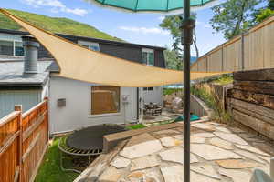 Rear view of house featuring a fenced backyard, a patio area, a shingled roof, a trampoline, and a mountain view