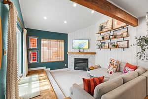 Carpeted living area with a fireplace, beamed ceiling, and recessed lighting