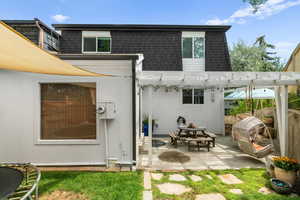Rear view of house featuring roof with shingles, mansard roof, a pergola, and a patio area