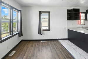 Unfurnished dining area with dark wood finished floors and a textured ceiling