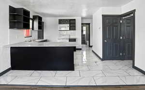 Kitchen featuring light stone countertops, a peninsula, white appliances, dark cabinets, and tasteful backsplash