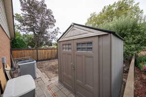 View of the west of the home with garden area and View of shed with a fenced backyard