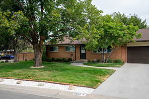 Single story home featuring concrete driveway, a garage, brick siding, and a shingled roof