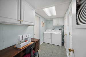 Laundry room with cabinet space, washing machine and clothes dryer, an office area, and light tile patterned floors