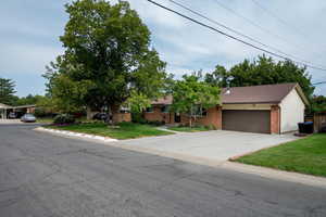 View of front of home featuring brick siding, a front yard, concrete driveway, and a garage