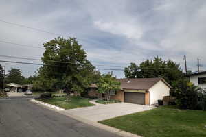 View of front of home with brick siding, concrete driveway, a front yard, and a garage