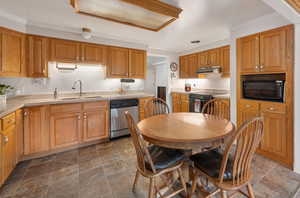 Kitchen featuring black & stainless steel appliances, ornamental molding, quartz countertops, under cabinet range hood, under cabinet lighting.