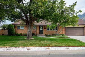 View of front of home with concrete driveway, an attached garage, a mountain view, brick siding, and a shingled roof