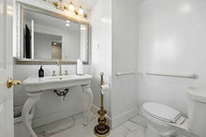 Half bathroom featuring marble look tile flooring and toilet