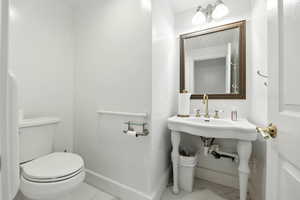 Half bath with toilet and marble finish floors